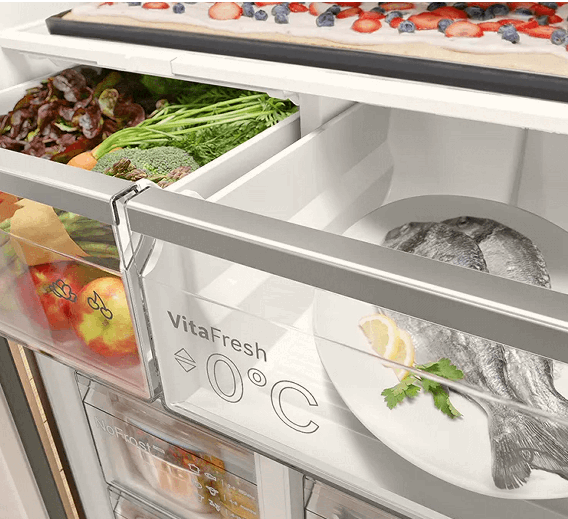 Zbliżenie na jedną z szuflad lodówki. Widoczne jedzenie: owoce, warzywa, ryby