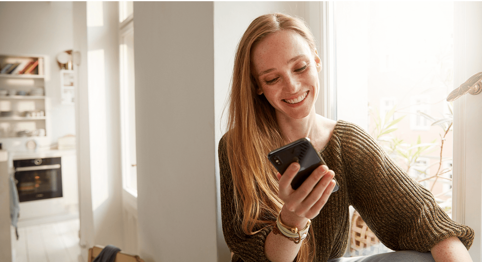 Kobieta używa smartfona do zdalnego ustawienia piekarnika Bosch