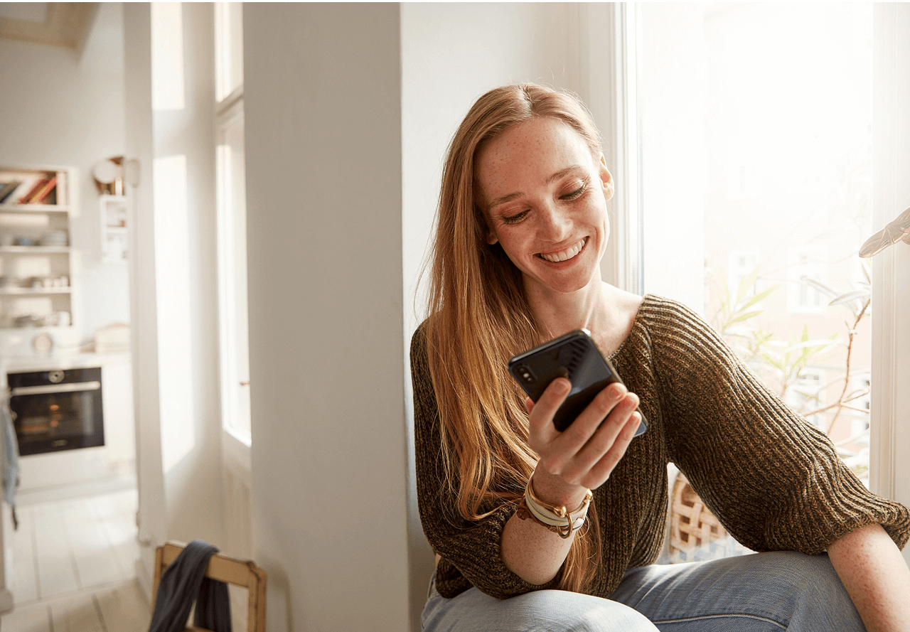 Kobieta używa smartfona do zdalnego ustawienia piekarnika Bosch
