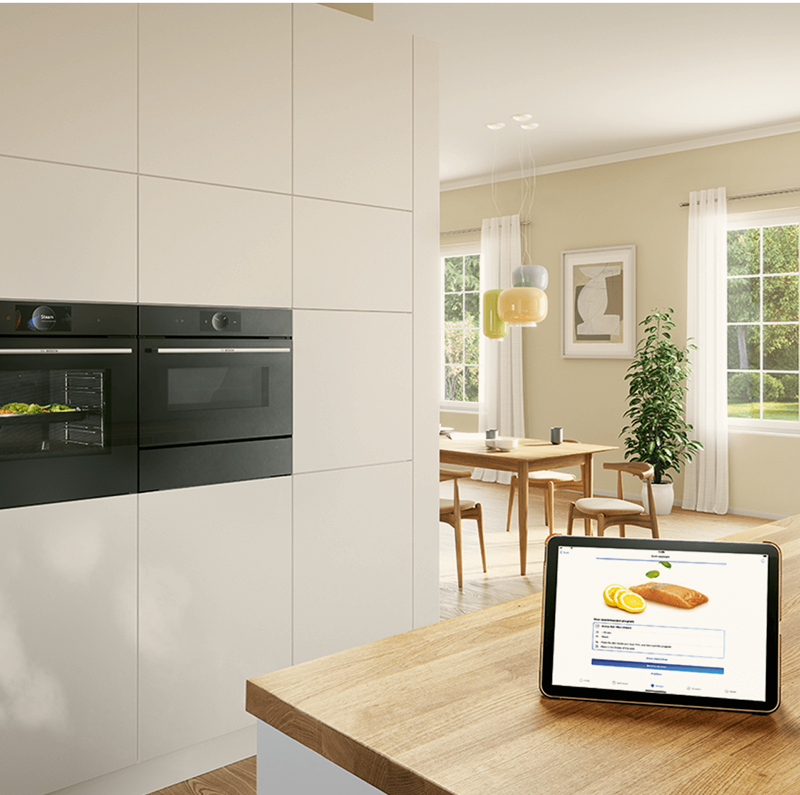 Dwa piekarniki Bosch z funkcją zdalnego sterowania w kuchni. Na blacie tablet z włączoną aplikacją