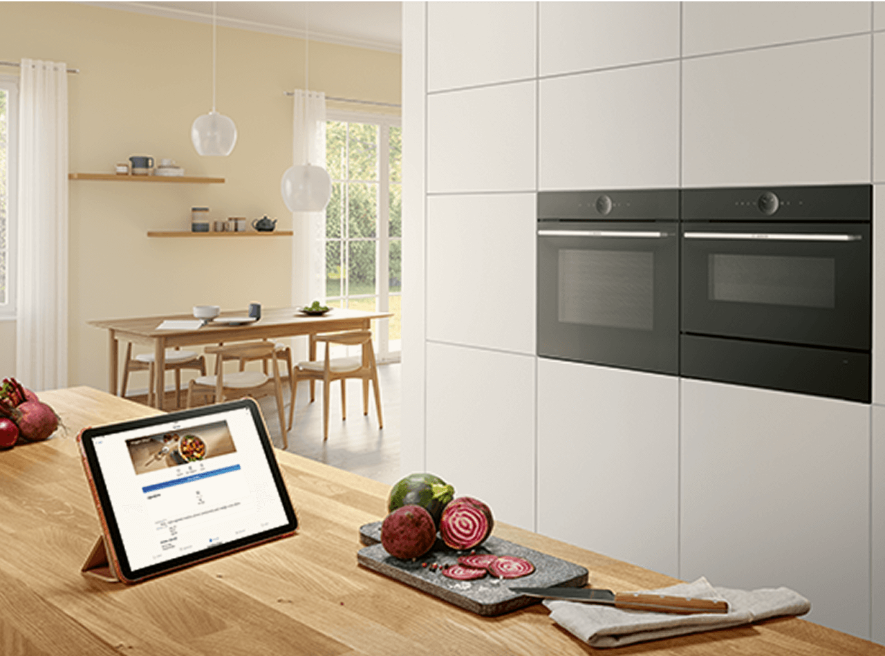 Piekarnik Bosch w nowoczesnej kuchni, sterowany przez tablet. Na tablecie włączony jest wybrany przepis