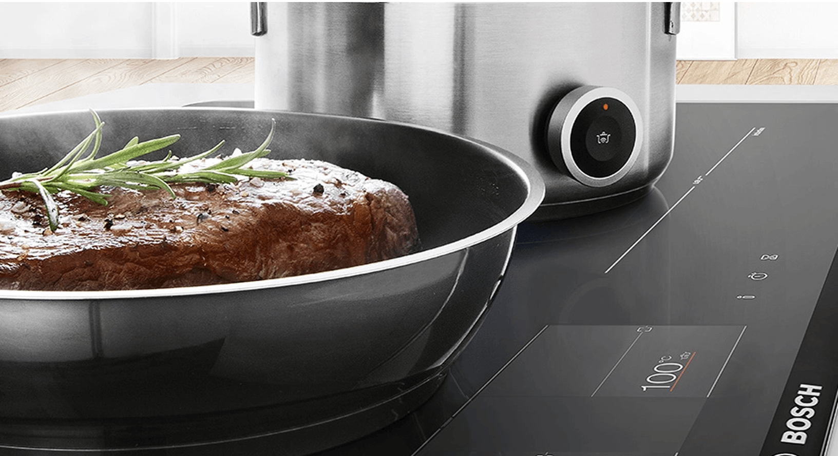 Zbliżenie na płytę indukcyjną Bosch z widocznymi polami grzewczymi. Na płycie stoją garnki z jedzeniem