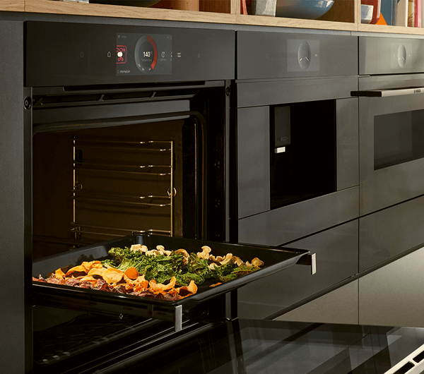 Smartfon z aplikacją Home Connect z otwartą zakładką z przepisami. W tle otwarty piekarnik.